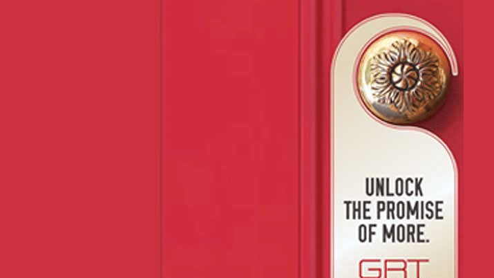 Marketing material with a red background and the tagline-Unlock the Promise of More- accompanied by a golden medallion emblem.