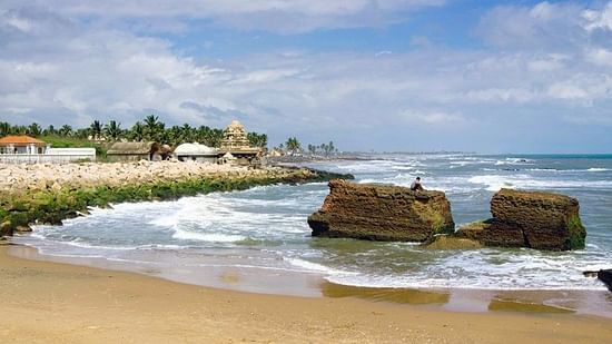 the beach with a large rock on the shore