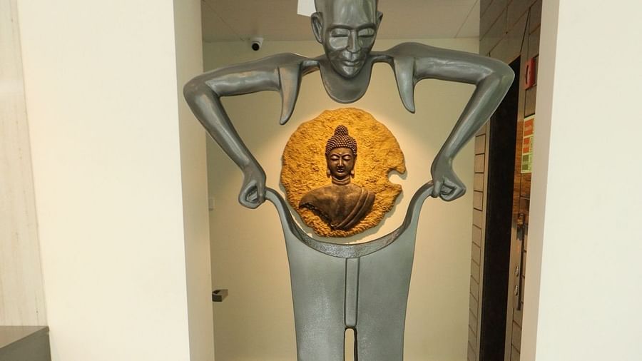 A tall, grey sculpture of a figure with an orange, circular centrepiece depicting a meditating Buddha - Sea Hills Hotels, Sri Vijaya Puram (Port Blair)