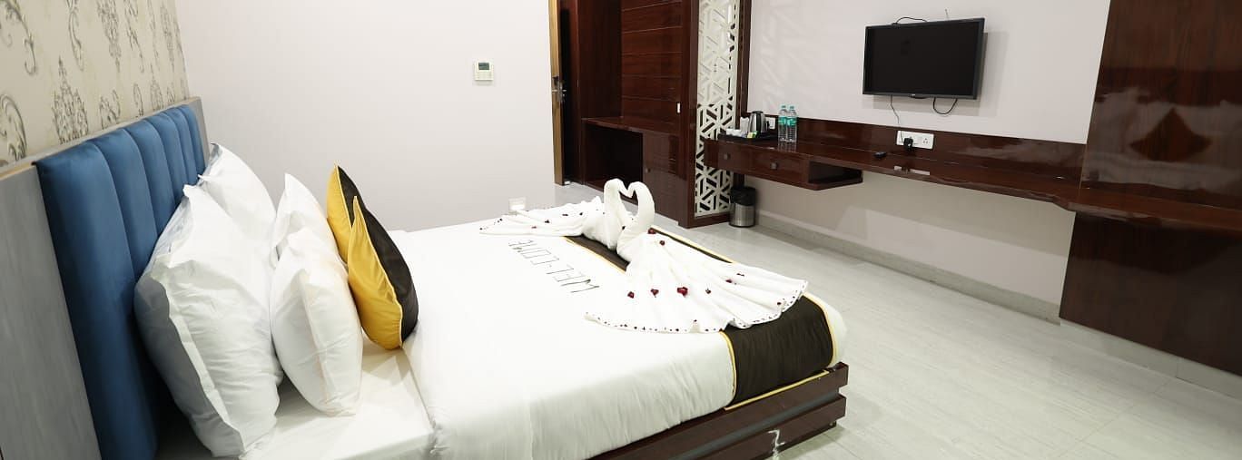 A bedroom at the Bamboo Saa Mulberry Resort featuring a bed with white linens, decorative pillows, and a wall mounted television.