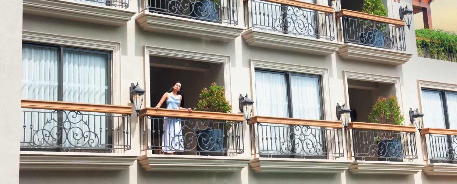 A woman standing in the balcony looking at the surrounding as she leans against the railing at The Evren, Vagator.
