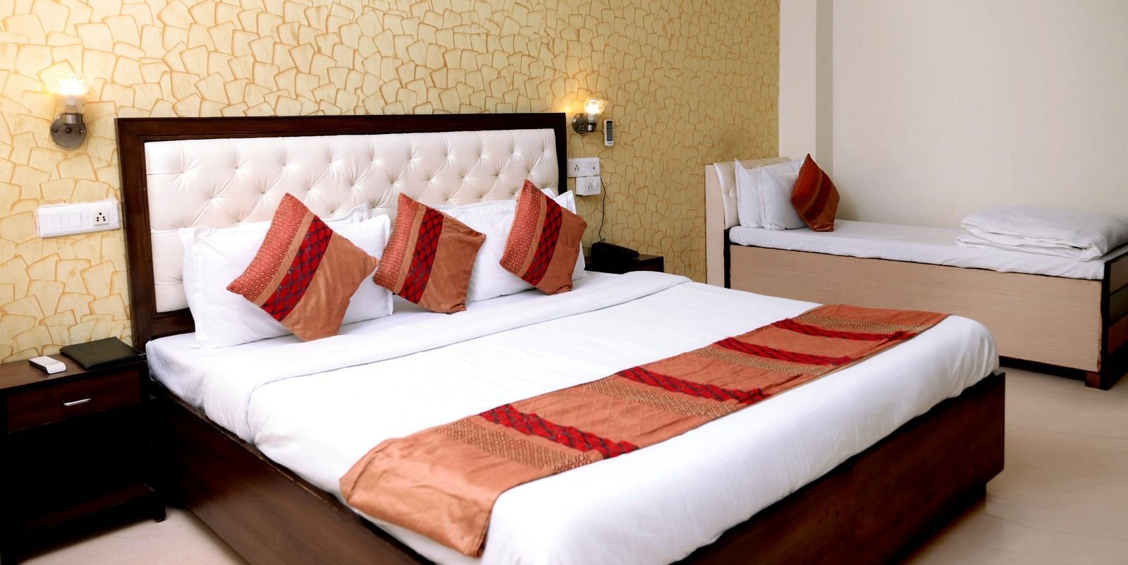 A luxurious hotel room with a king-size bed, golden accent wallpaper, warm lighting, and a modern aesthetic - Hotel Diamond Inn, Chandigarh