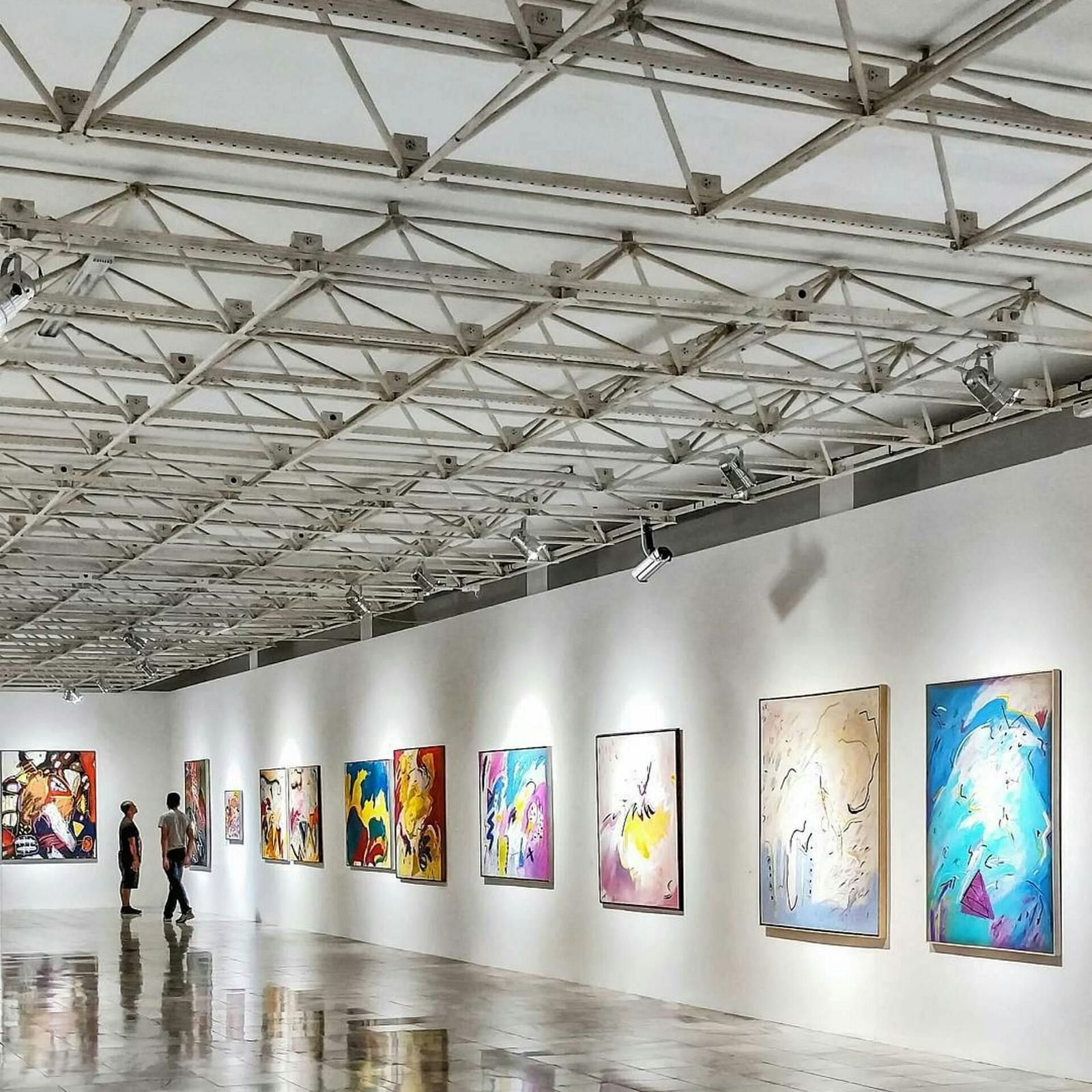 A well-lit room hosting an art exhibition, with pieces displayed on the walls