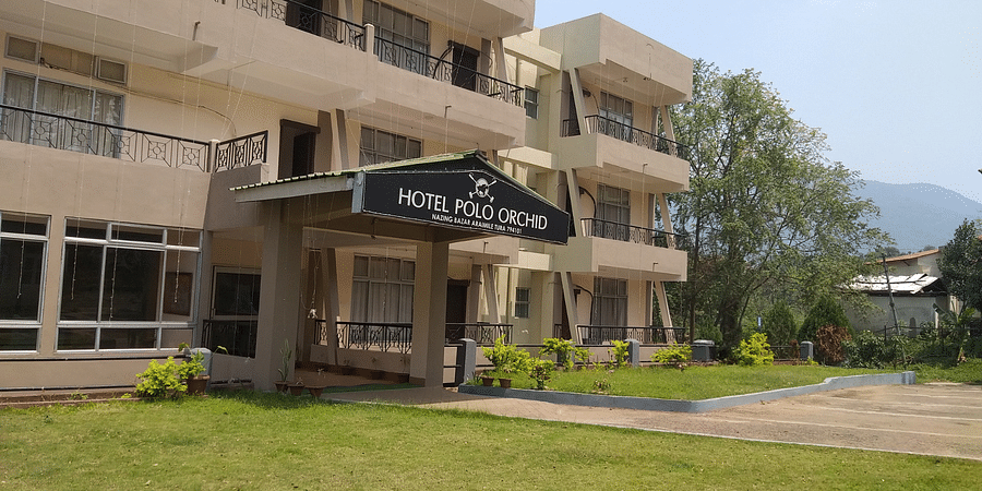 alt-text A side view of Hotel Polo Orchid showing its multi-story beige facade with balconies and surrounding greenery.