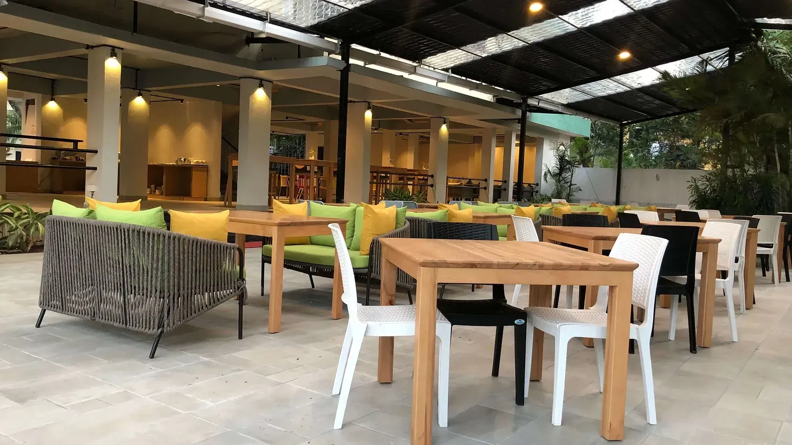 Dining seating with wooden chairs around tables in Aqua Vida Restaurant at Indie Stays Resort, Goa.