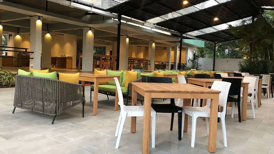 Dining seating with wooden chairs around tables in Aqua Vida Restaurant at Indie Stays Resort, Goa.
