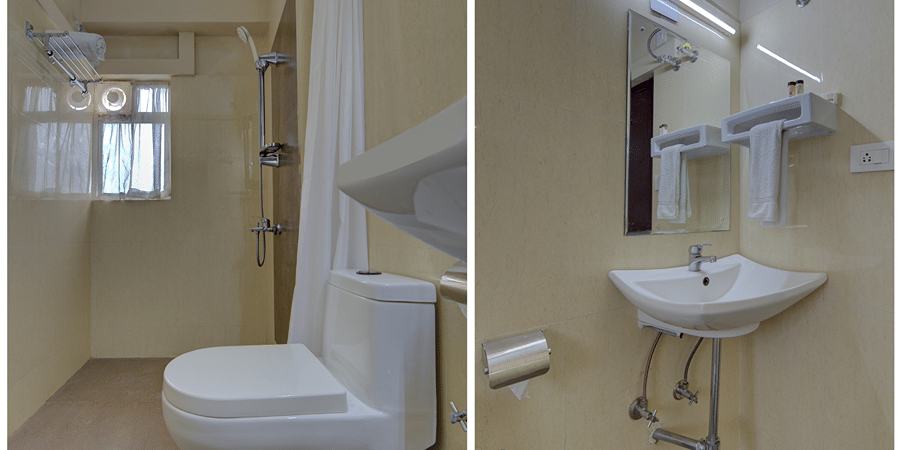 A bathroom at Central Courtyard Boutique Hotel, Siliguri, featuring a toilet nd a sink with mirror above