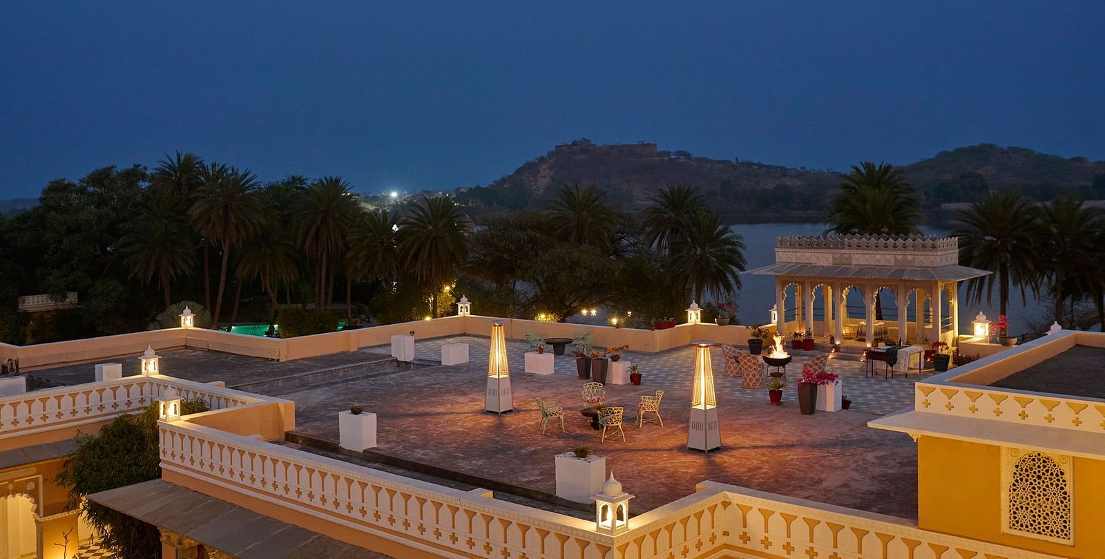 image of the terrace at dev shree, deogarh at a night time overlooking the a lake in front of the facade