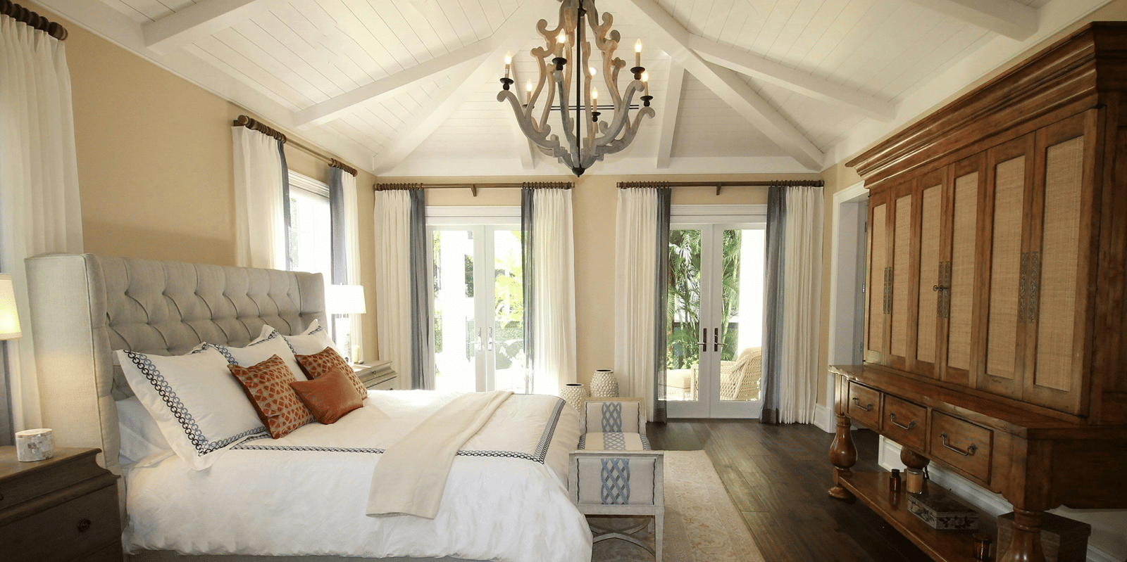 Side view image of the bed with a chandelier hanging over the double bed.