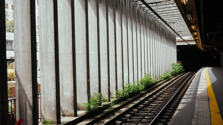 Metro tracks running past a platform lined with concrete pillars towards a dark tunnel