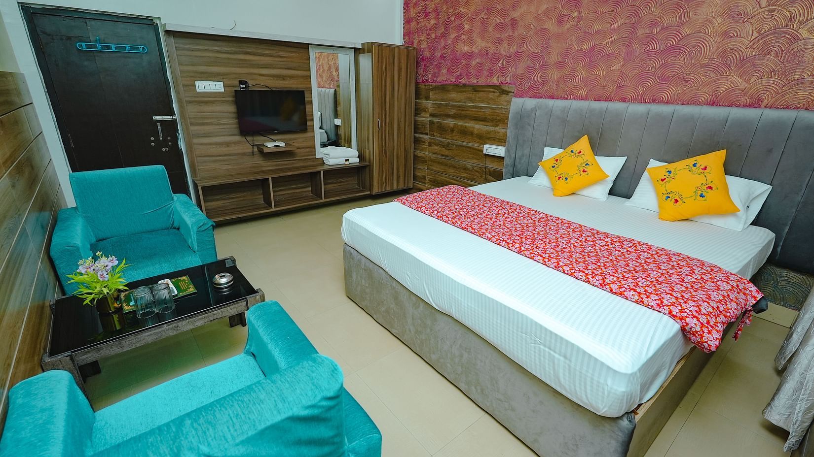 An image of a bedroom featuring a double size bed, a dressing table, a wardrobe, a flat TV screen, and a seating area with sofa and a centre table - Rangamati Garden Resort