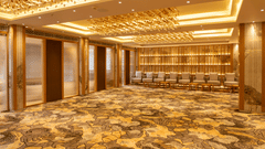 The luxurious ballroom at Pride Elite Himmatnagar features intricate ceiling lights and a patterned carpet floor.