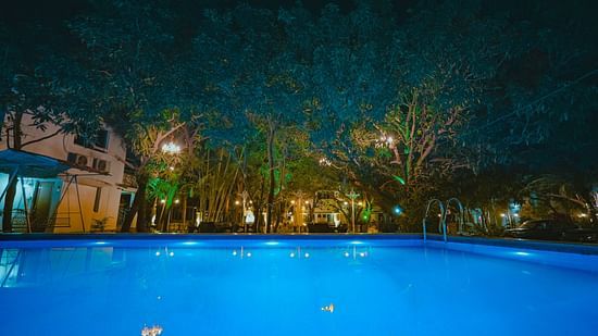 An image of a Swiming Pool with having some trees around and a building at Rangamati Garden Resort