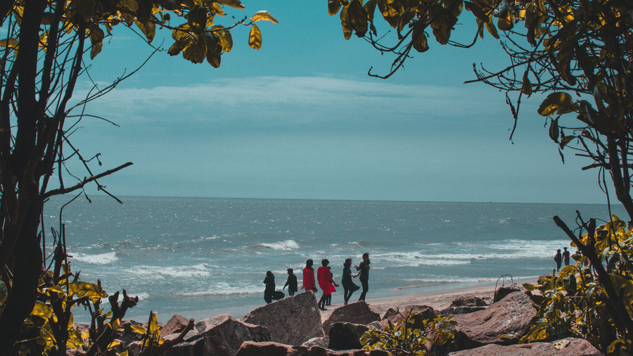 A few people standing on the coast of Kozhikode Beach
