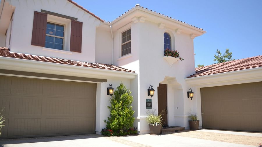 Overview shot of a villa with a entrance door and parking shutter with a backdrop of clear blue sky.