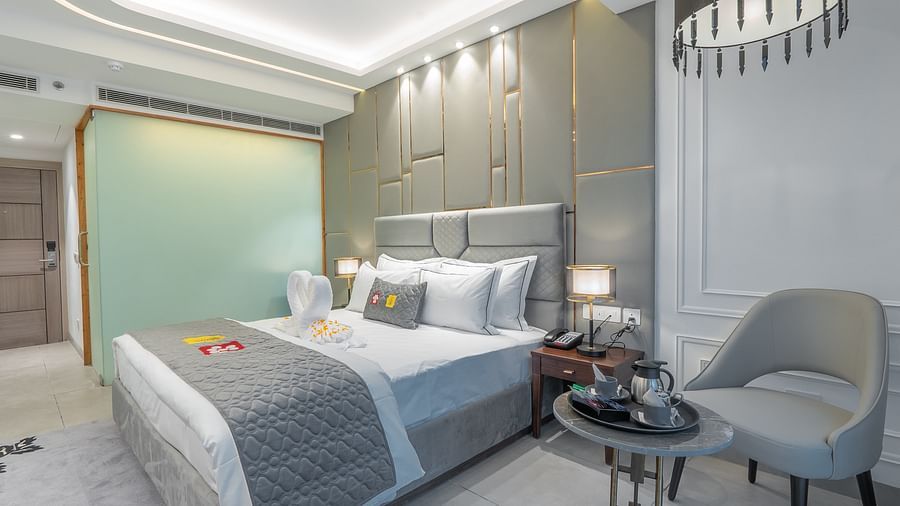 A well-decorated, contemporary bedroom with a large bed, stylish chair, and modern lighting fixtures at Mastiff Select Mandavya Dharamkot, McLeodgan