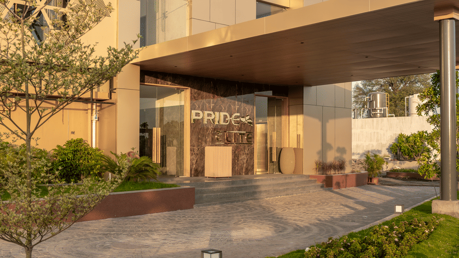 The grand entrance of the hotel features a canopy and manicured greenery - Pride Elite Himmatnagar, Gujarat