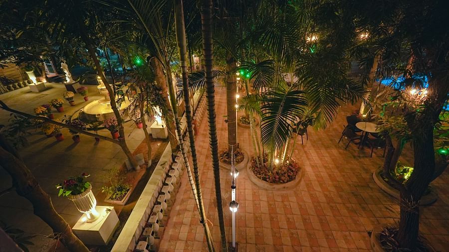 An image of outdoor garden surrounded by trees where tables and chairs are placed at Rangamati Garden Resort