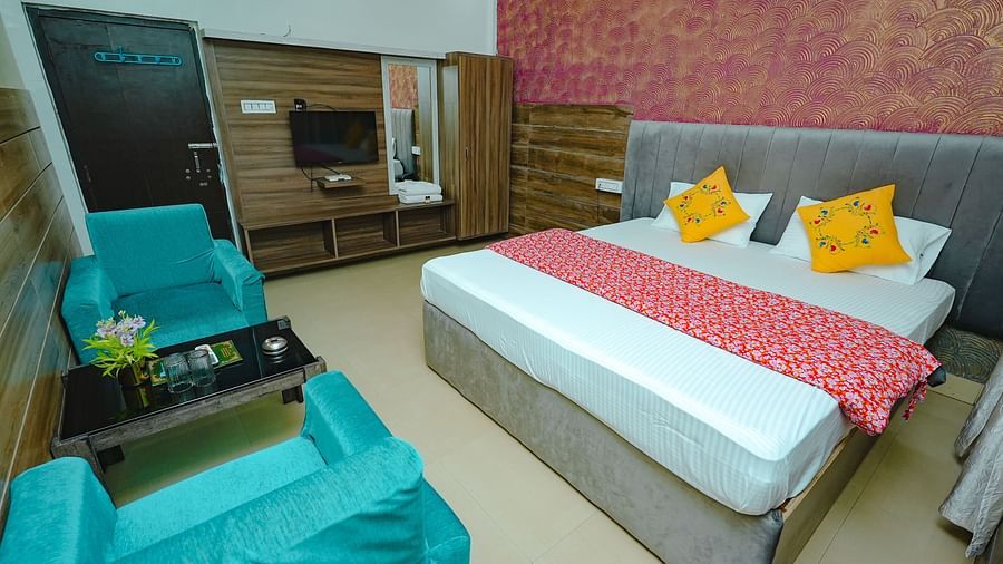 An image of a bedroom featuring a double size bed, a dressing table, a wardrobe, a flat TV screen, and a seating area with sofa and a centre table - Rangamati Garden Resort