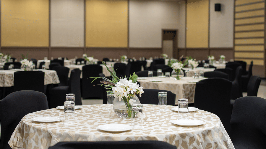 Dining setup with tablecloths and place settings on round tables in a banquet setting at The Golden Tusk, Jim Corbett