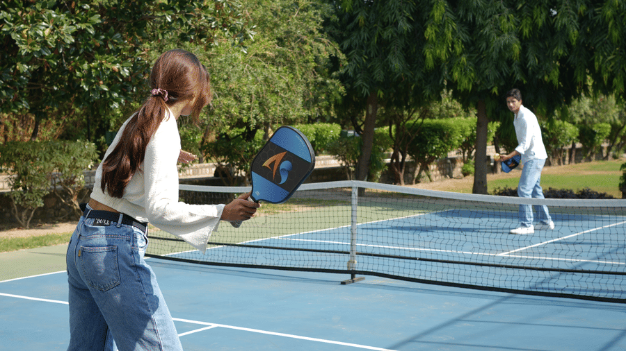 People playing pickleball on a outdoor court enclosed by a fence at The Golden Tusk, Jim Corbett