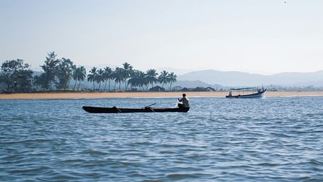 a fisherman pulling a fishing net with palolem beach in the background