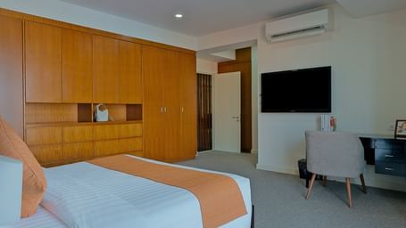 A modern room with a large bed, a wooden headboard, and a flat-screen TV | Penthouse | Central Mansions, Phnom Penh