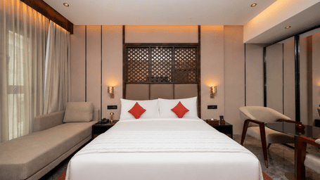 Amber room featuring a king bed alongside a window lounge daybed at Ni Central Park, Mysuru.