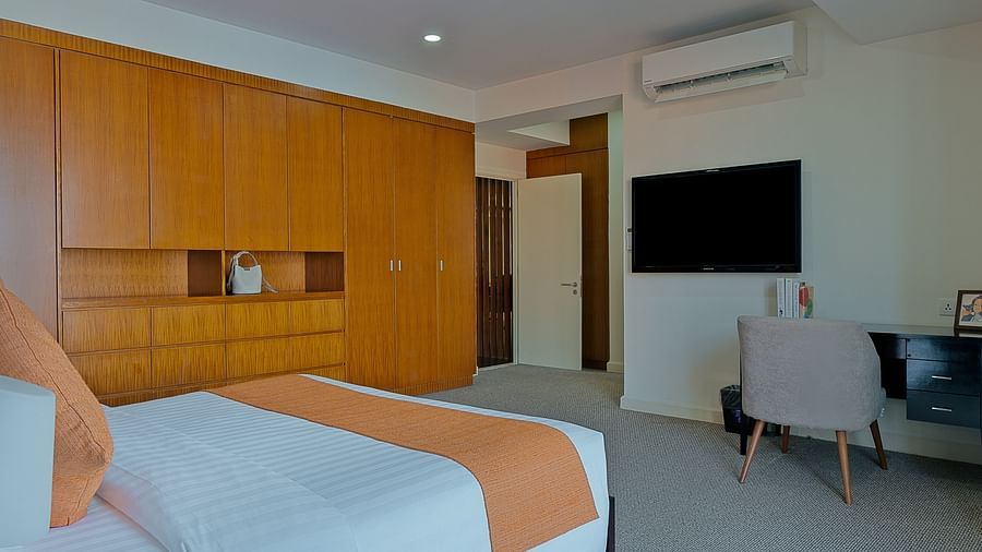 A modern room with a large bed, a wooden headboard, and a flat-screen TV | Penthouse | Central Mansions, Phnom Penh