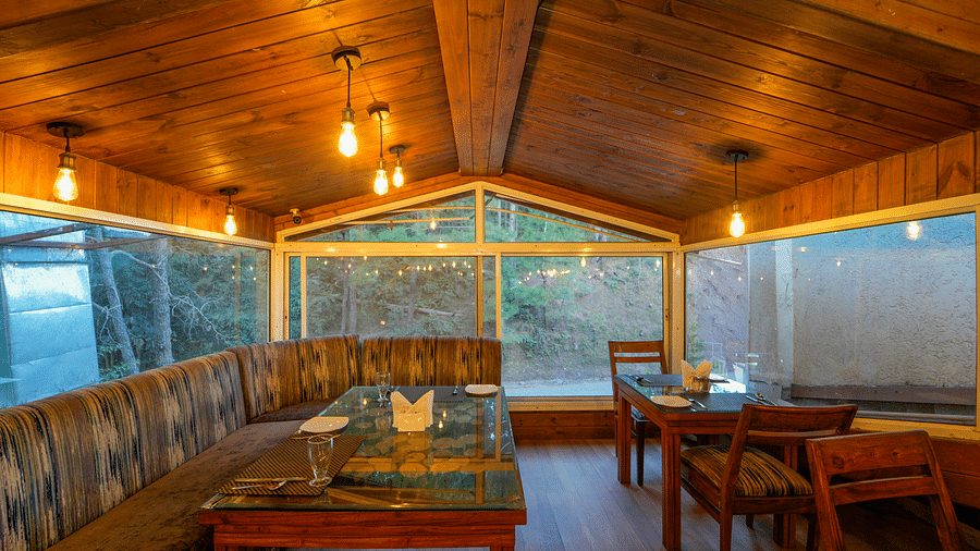 An image of the restaurant at DLS Whispering Winds with the set up of chairs and tables and the backdrop of the view from the expansive glass windows