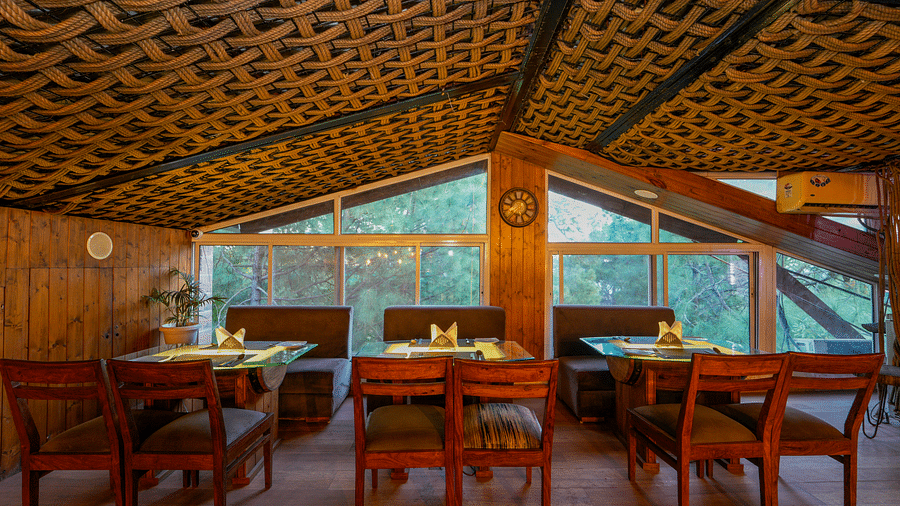A shot of Ruttba, the restaurant at DLS Whispering Winds featuring chairs and tables and expansive glass windows viewing the scenic backdrop