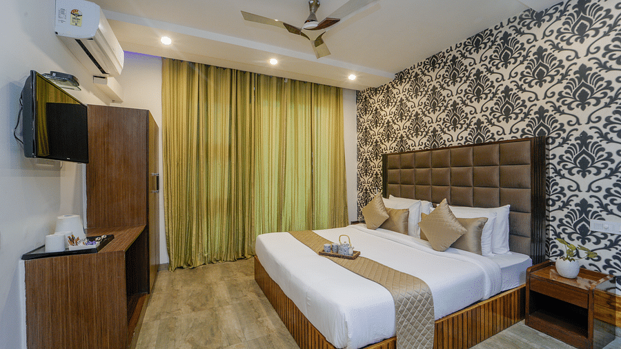 The deluxe room at DLS Whispering Winds showcasing a bed, a bed side table, and a flat screen TV along with other room amenities