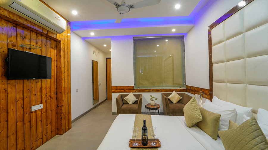 An image of the premium room with a bed, two single sofa chairs, a flat screen TV, and air-conditioning - DLS Whispering Winds