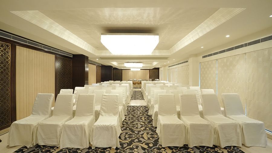 A spacious event hall with many chairs covered in white fabric, arranged on a patterned carpet - Fragrant Nature Cochin