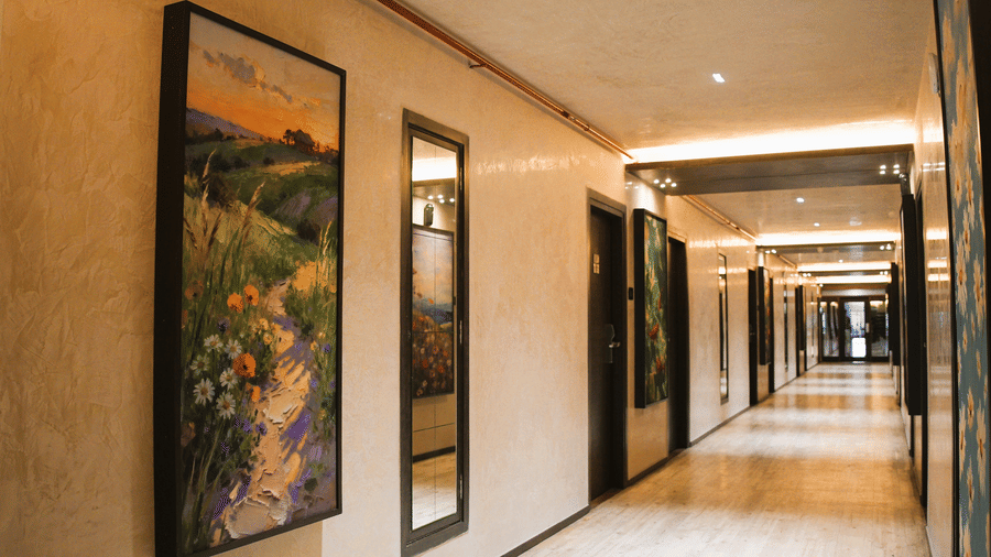 An elongated path with several wall hanging art works. | Infiniti Hotel, Indore