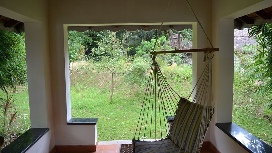 a cot inside a small shed with gardens outside - Kadkani River Resort, Coorg