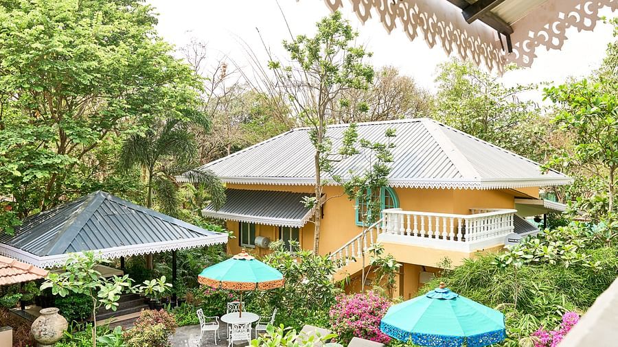 Facade view of Mayfair Manor, Alibag, with trees and plants surrounding the area