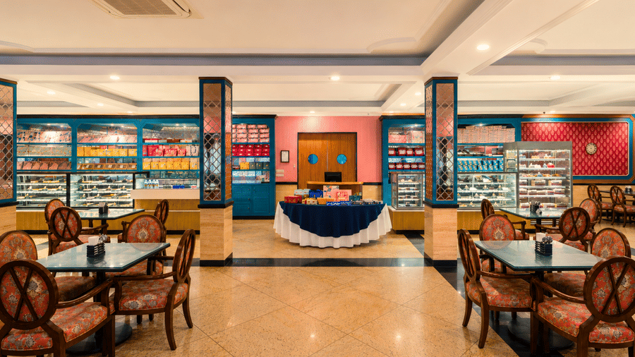 Bakery and confectionery shop with glass display counters, shelves of gift boxes and cafe tables and chairs at MAYFAIR Oasis Resort & Convention, Jharsuguda.