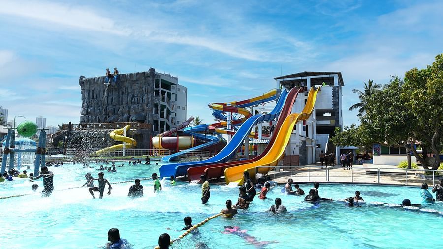 Side view of swimming pool with slides and people playing