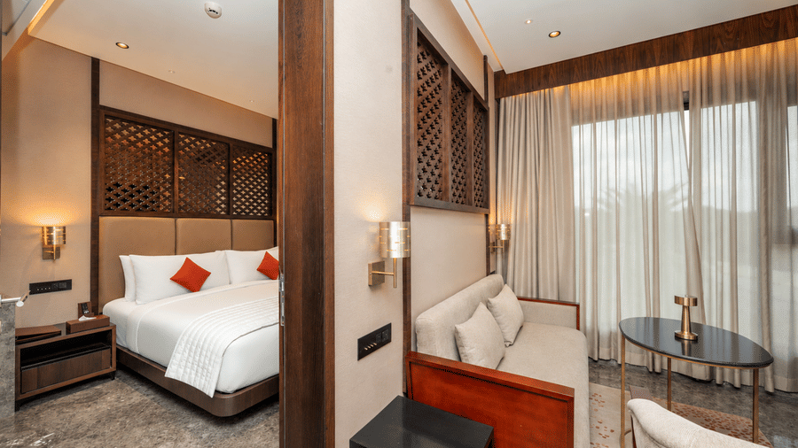 Zari Suite bedroom featuring a plush sofa bed and contemporary wooden wall accents at Ni Central Park.