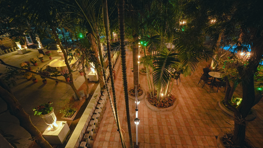 An elevated view of an outdoor resort pathway beautifully lit by lamps nestled among trees at night.