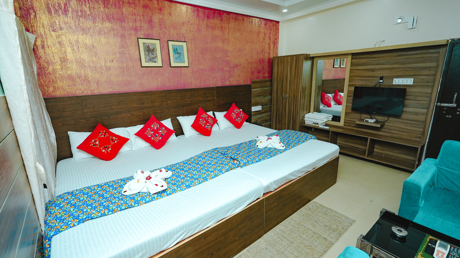 A colourful resort hotel room featuring a large double bed with red cushions, a textured red feature wall, and wooden furniture.