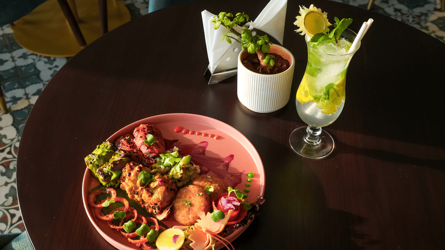 A round table with a plate of cooked food and two glasses containing a beverage.