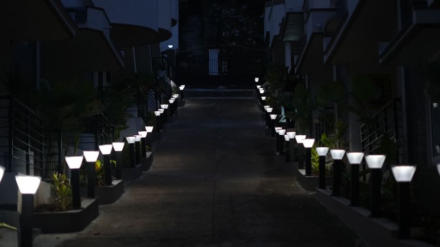 A dark exterior shot of WOW Naturefull Resorts featuring a pathway in the middle along with white exterior lights lining the pathway.