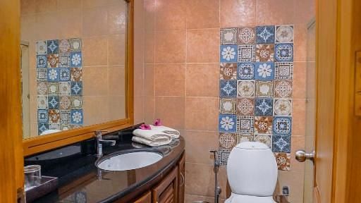  Bathroom with a mirror above the washbasin, separate lighting for it, and a glass partition separating the shower area.