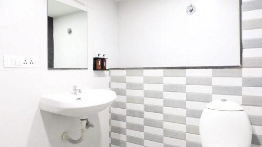 Full view of a brightly lit bathroom featuring a wash basin along with a commode in the corner at Pravasa Ahmedabad.