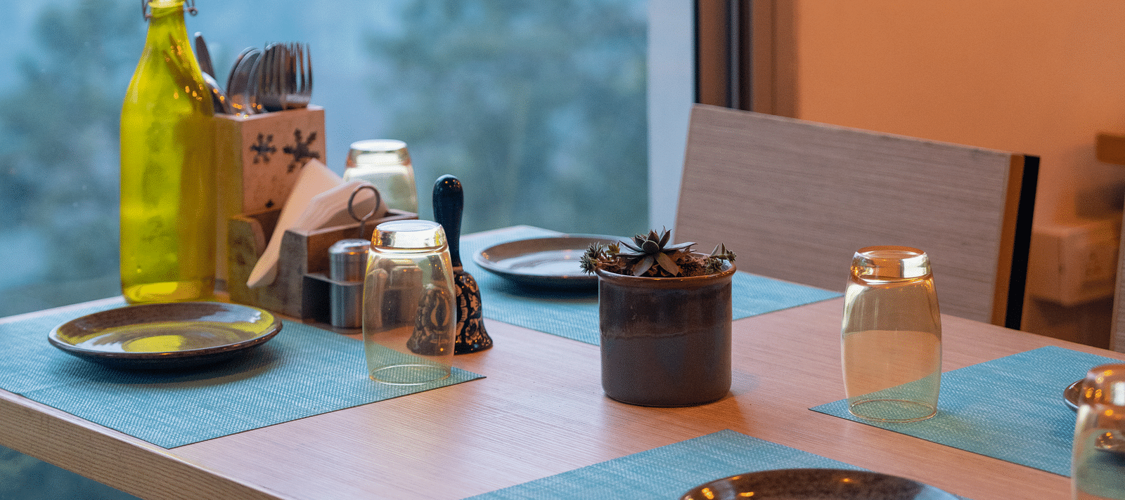 Restaurant table set with a glass bottle and plates at BluSalzz Escapade Resort, Lansdowne.