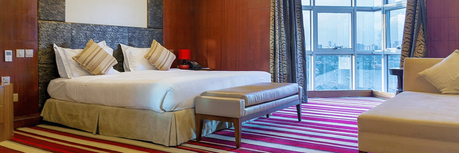 King size bed with striped carpet in a well lit bed room at The Boma Nairobi.