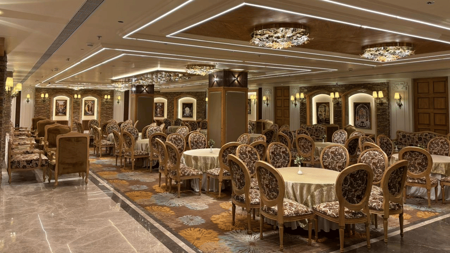 Banquet hall at Presidium Sarovar Premiere, Dalhousie with round dining tables and elegant ceiling lights.