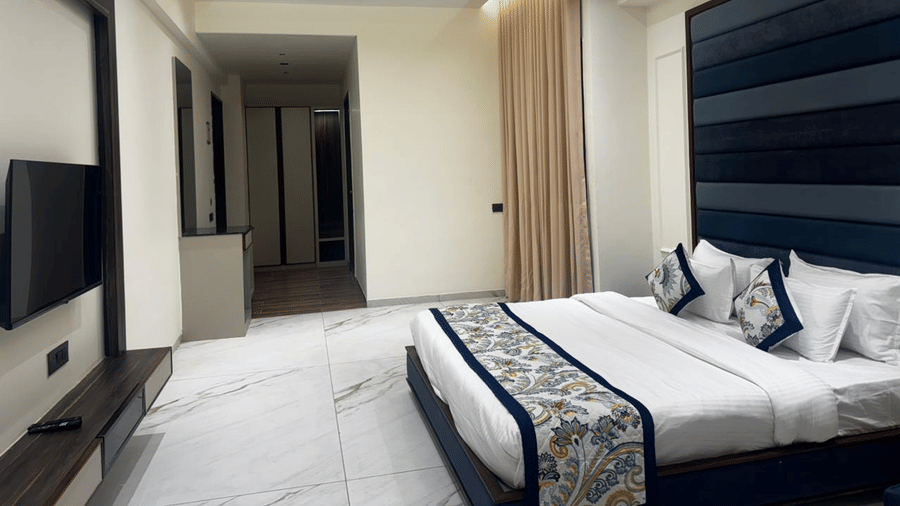 Modern bedroom with a flat-screen TV and stylish headboard - Lords Swastik Studio, Kodinar